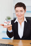 Portrait of a businesswoman showing a miniature house 