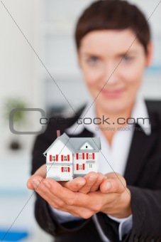 Portrait of a businesswoman holding a miniature house
