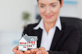 Smiling businesswoman holding a miniature house