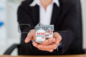 Feminine hands holding a miniature house