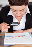 Businesswoman looking at a chart with a magnifying glass