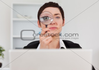 Office worker looking through  a magnifying glass