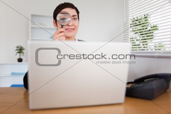 Businesswoman looking through  a magnifying glass
