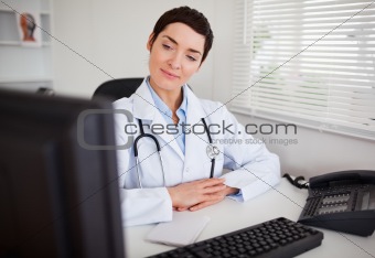 Serious female doctor looking at her computer