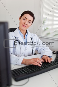 Portrait of a charming female doctor typing with her computer