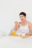 Portrait of a cute woman eating cereal while looking at the came