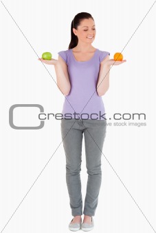 Good looking woman holding fruits while standing