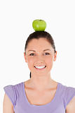 Portrait of an attractive woman holding an apple on her head whi