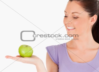 Charming woman holding an apple while standing