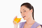 Attractive woman drinking a glass of orange juice while standing