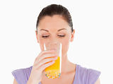 Good looking woman drinking a glass of orange juice while standi