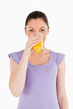 Pretty woman drinking a glass of orange juice while standing
