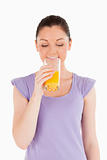 Charming woman drinking a glass of orange juice while standing