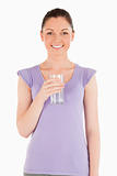 Charming woman holding a glass of water while standing
