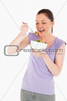 Beautiful woman eating a bowl of salad while standing