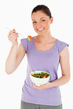 Attractive woman eating a bowl of salad while standing
