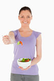 Good looking woman holding a bowl of salad while standing