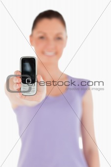 Beautiful woman holding and showing her phone while standing