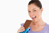 Portrait of a good looking woman eating a chocolate block while 