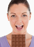 Portrait of an attractive woman eating a chocolate block while s
