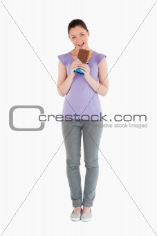Lovely woman eating a chocolate block while standing