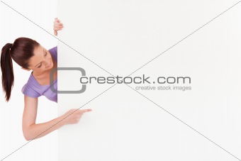 Cute female pointing at a copy space while standing