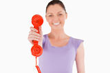 Beautiful woman holding a red telephone while standing