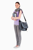 Attractive student holding books and her bag while standing