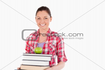 Beautiful female holding and a apple and books while posing