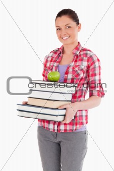 Attractive female holding and a apple and books while posing