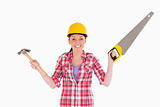 Pretty woman holding a saw and a hammer while standing