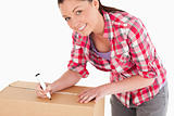 Portrait of an attractive woman writing on cardboard boxes with 