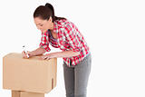 Attractive woman writing on cardboard boxes with a marker while 
