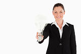 Attractive woman in suit holding a light bulb while standing