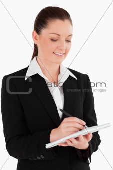 Portrait of a gorgeous woman in suit writing on a notebook