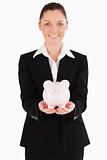 Beautiful woman in suit holding a pink piggy bank