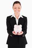 Good looking woman in suit holding a pink piggy bank