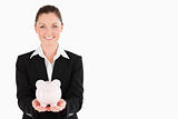 Charming woman in suit holding a pink piggy bank