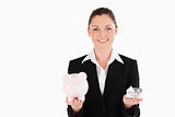 Beautiful woman in suit holding a piggy bank and a miniature hou