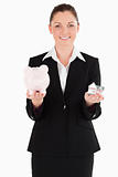 Attractive woman in suit holding a piggy bank and a miniature ho