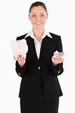 Good looking woman in suit holding a piggy bank and a miniature 