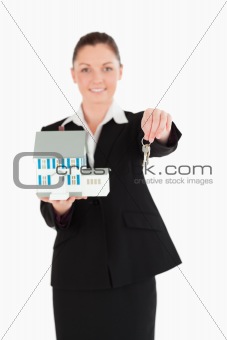 Pretty woman in suit holding keys and a miniature house
