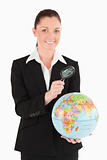 Attractive female in suit holding a globe and using a magnifying