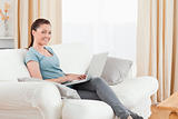 Good looking woman relaxing with her laptop while sitting on a s