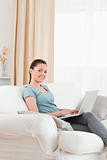 Lovely woman relaxing with her laptop while sitting on a sofa