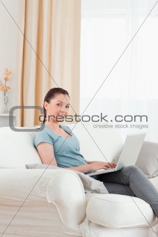 Lovely woman relaxing with her laptop while sitting on a sofa