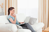Beautiful woman relaxing with her laptop while sitting on a sofa