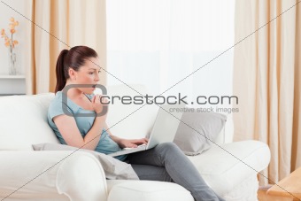 Surprised woman gambling with her computer while sitting on a so