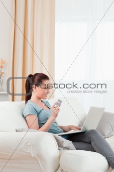 Cute woman making an online payment with her credit card while s