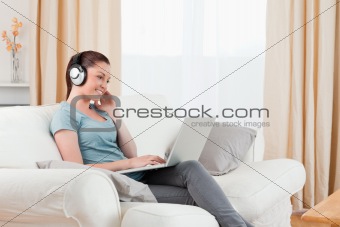 Attractive woman with headphones relaxing with her laptop while 
